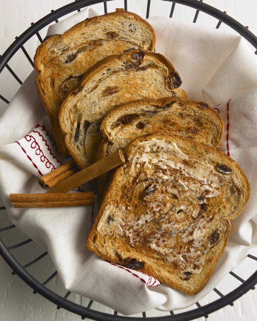 Buttered Cinnamon Raisin Toast in a Wire Basket with Cinnamon Sticks