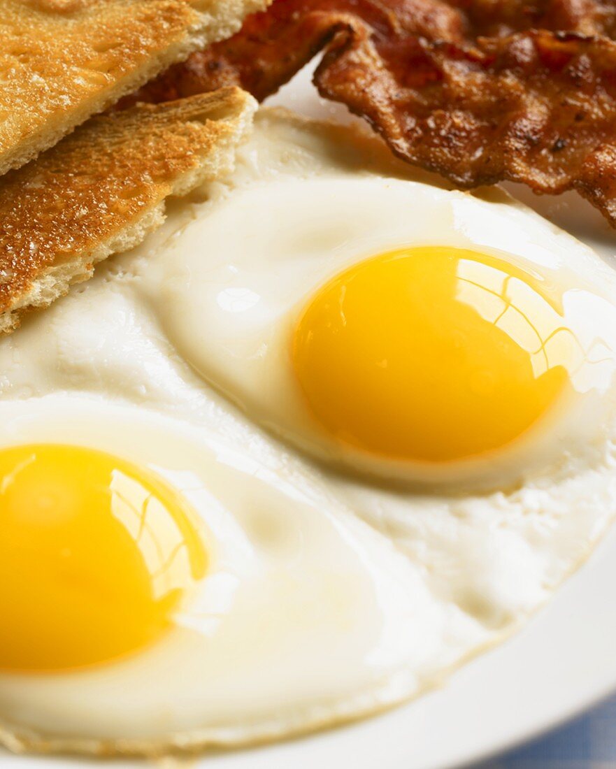 Two Sunny Side Up Fried Eggs with Toast and Bacon, Close Up
