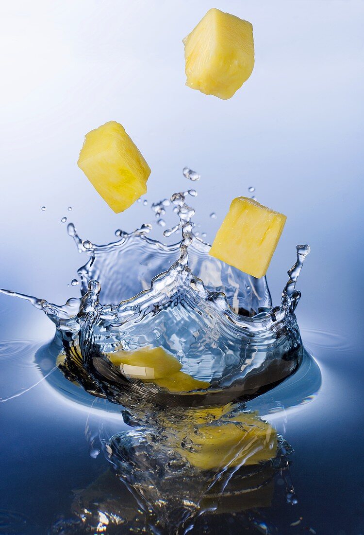 Pineapple chunks falling into water