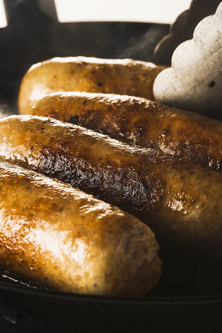 Sausages being fried in a pan