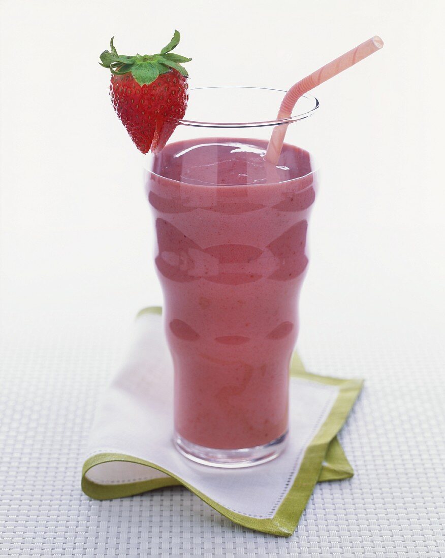 Berry smoothie in a glass with a straw and a strawberry