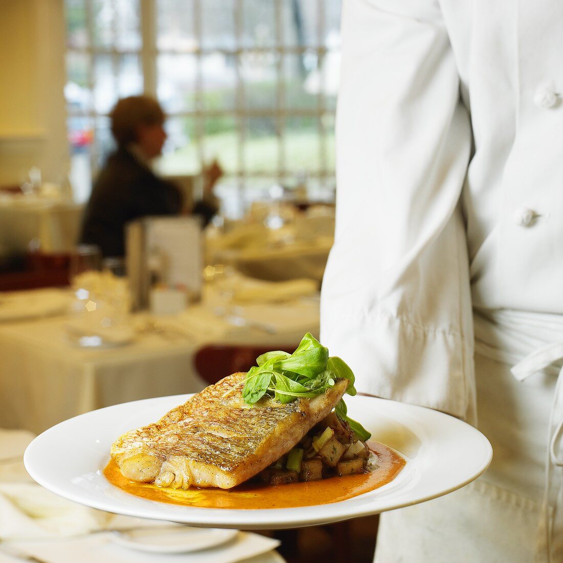 Chef serving red snapper on herb potatoes in restaurant