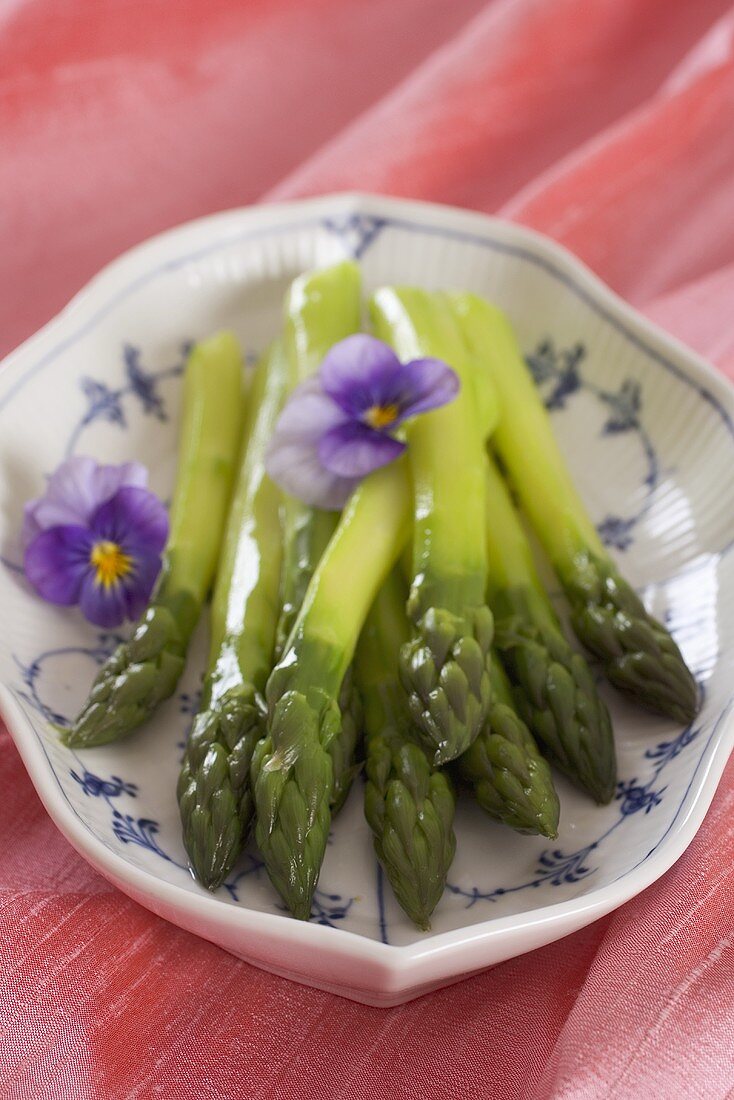 Gedämpfter grüner Spargel, dekoriert mit Veilchen