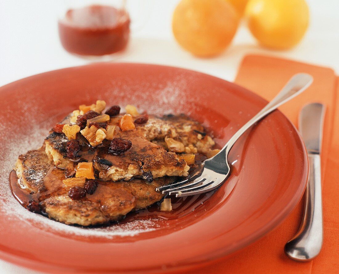 Granola Pancakes Topped with Dried Fruit and Maple Syrup