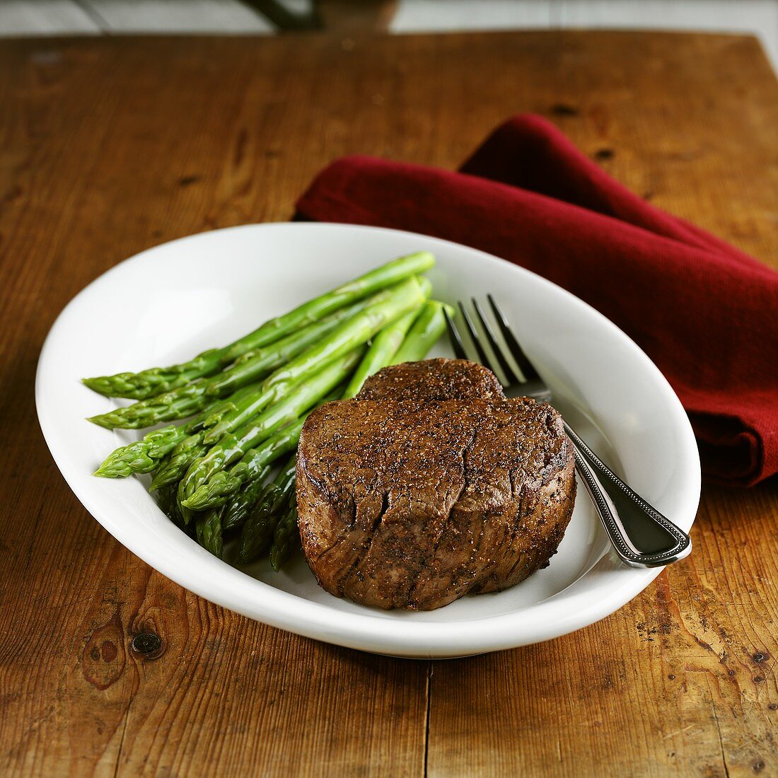 Beef fillet with green asparagus on wooden table