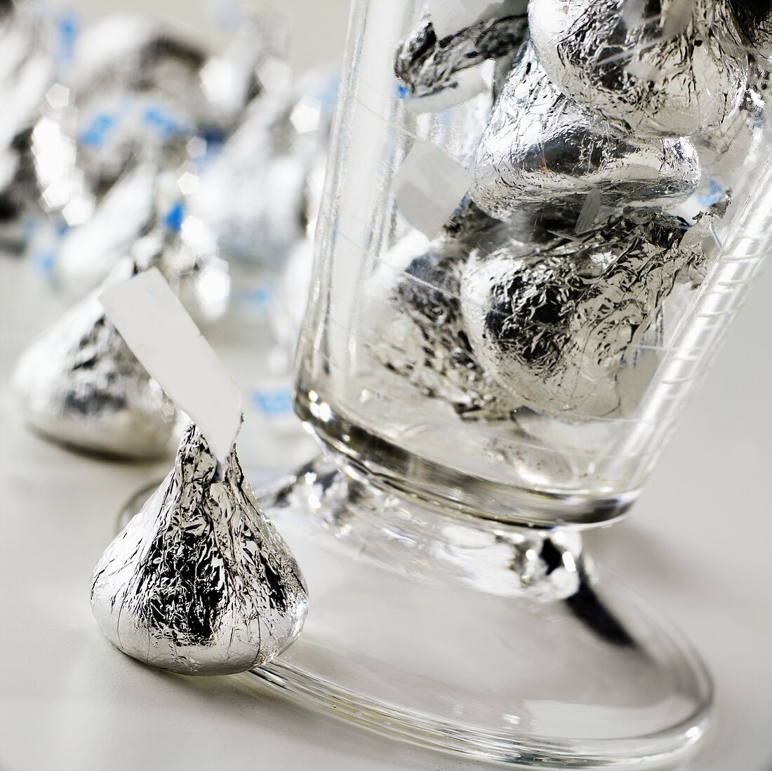 Schokoladenbonbons in einem Glas und daneben leigend