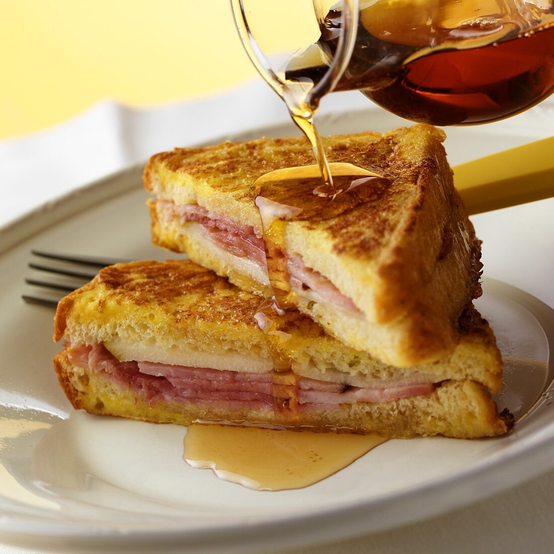 Pouring maple syrup over French toast with ham