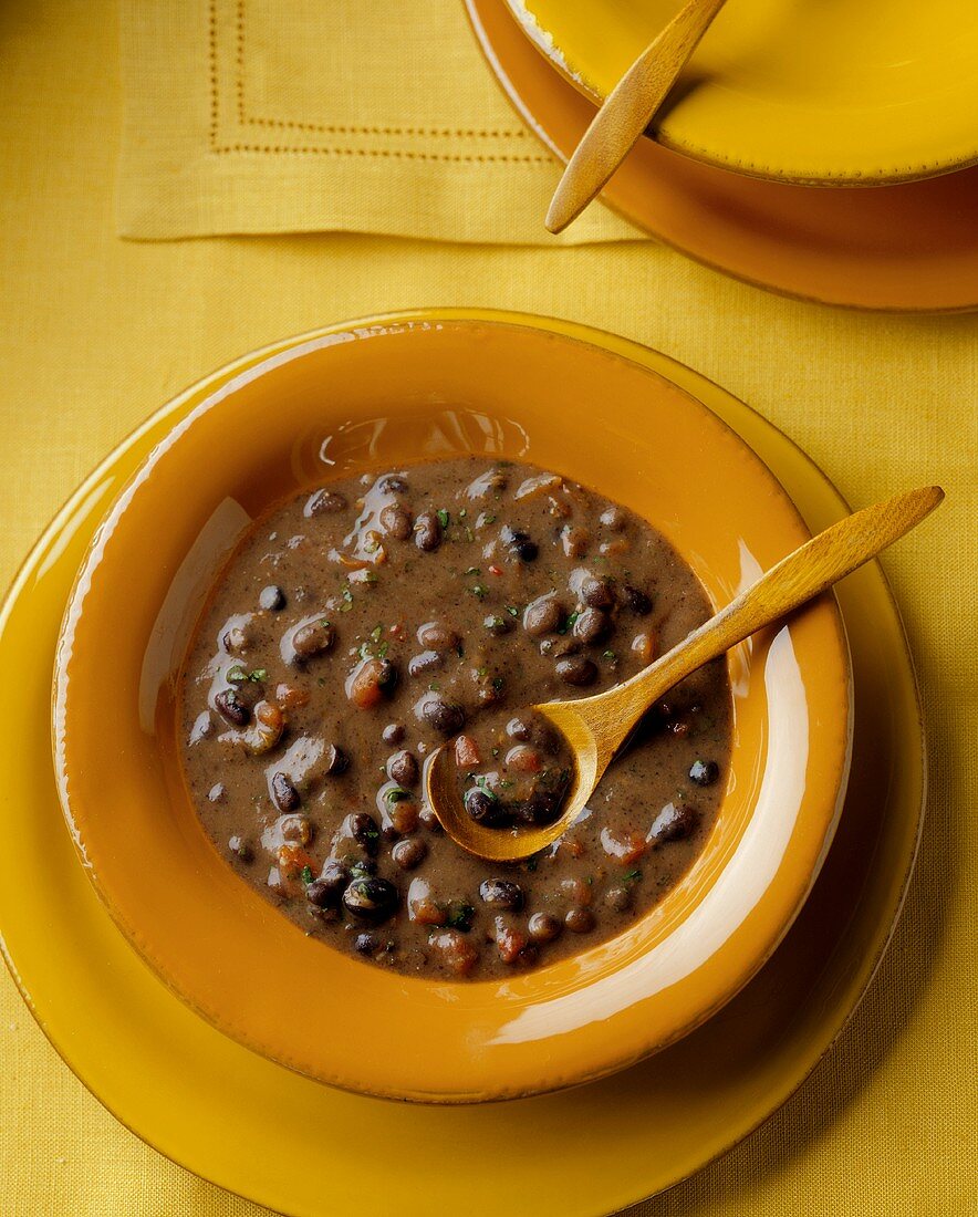 A Bowl of Black Bean Soup with a Wooden Spoon
