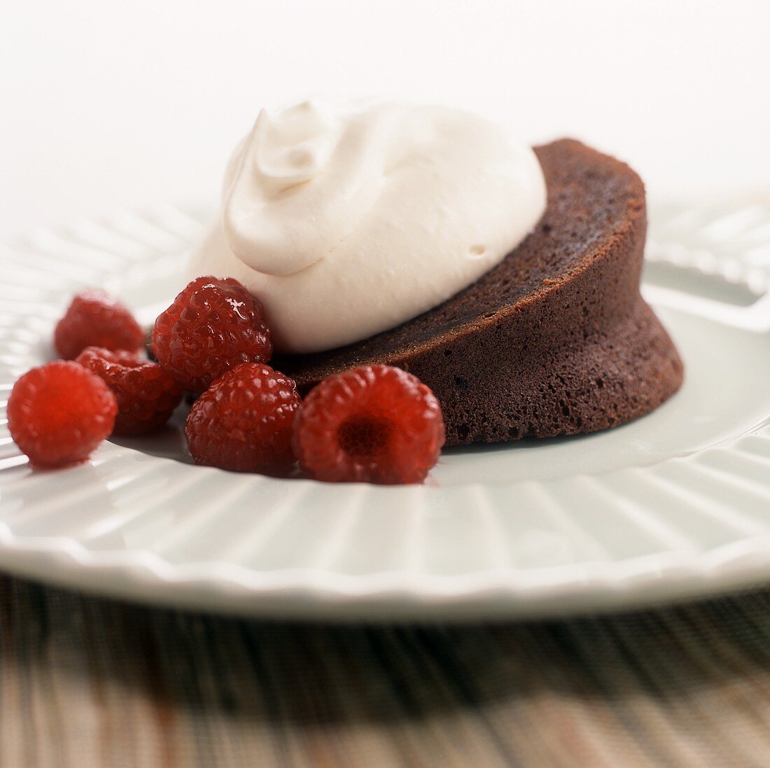 Stück Schokoladennapfkuchen mit Sahne und Himbeeren