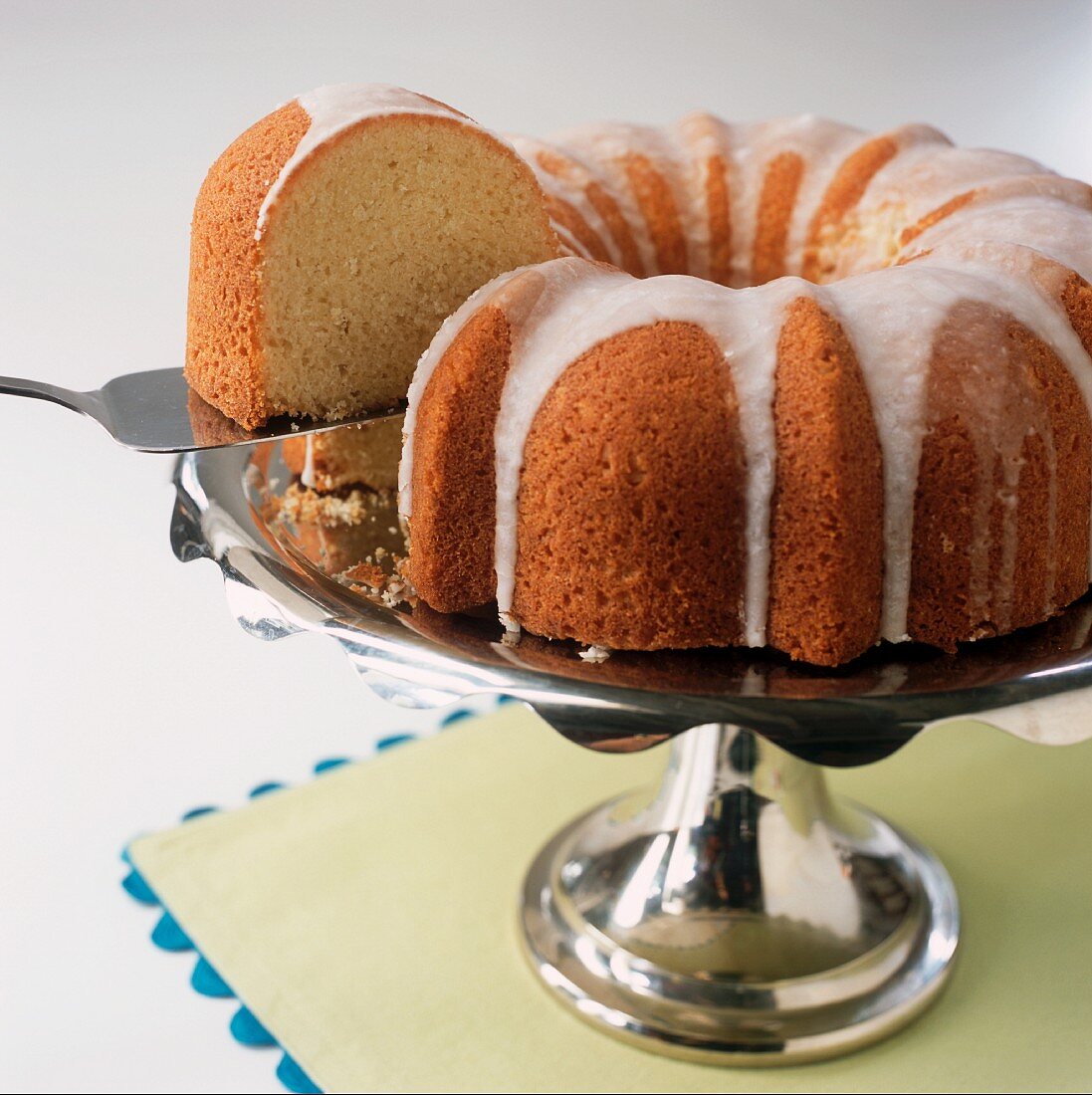 Lifting a Slice of Bundt Cake from a Whole Iced Bundt Cake