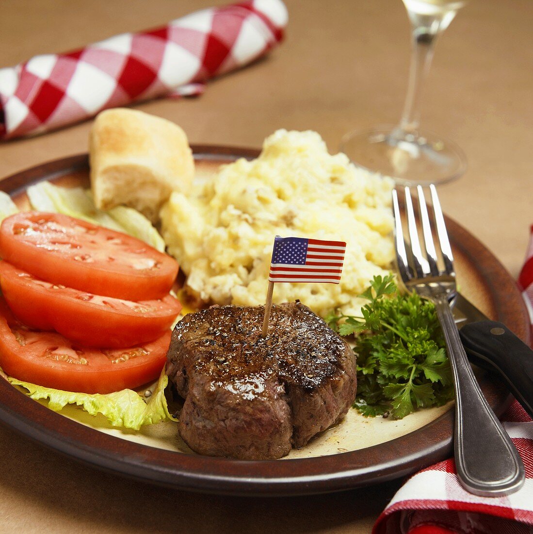 A Steak Fillet with an American Flag Toothpick, Mashed Potatoes and Tomatoes