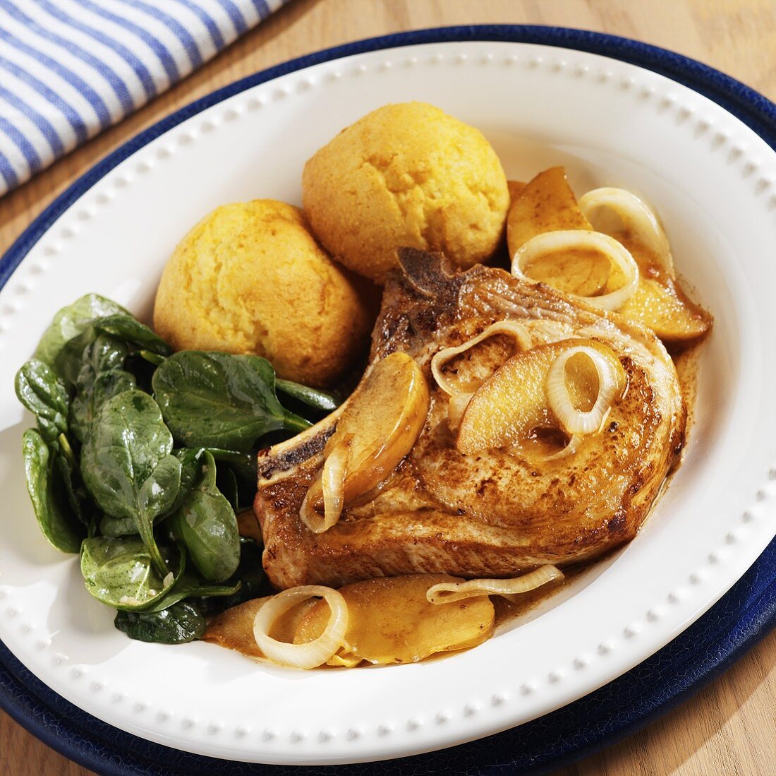 A Pork Chop with Apple and Onion Glaze with Biscuits and Baby Spinach