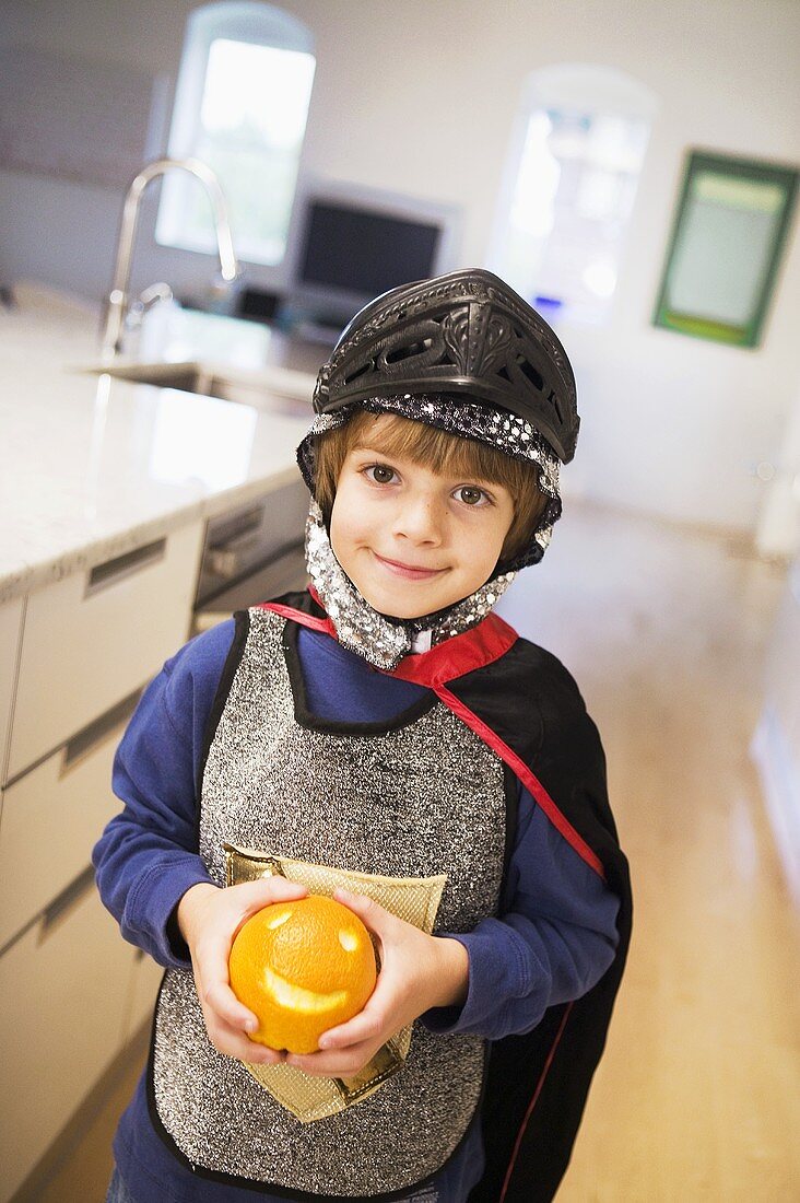 Kleiner Junge, als Ritter verkleidet, hält Orange