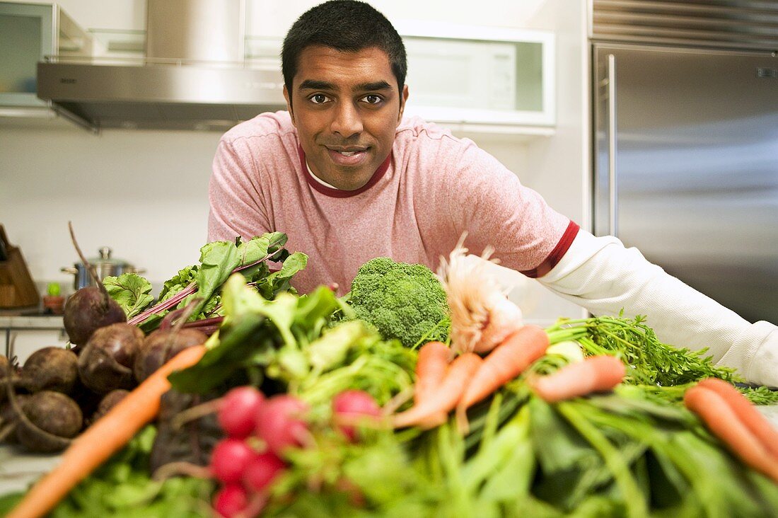 Mann blickt über einen Haufen Gemüse in der Küche