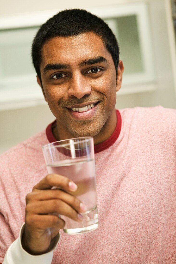 A Man Smiling and Holding a Glass of Water