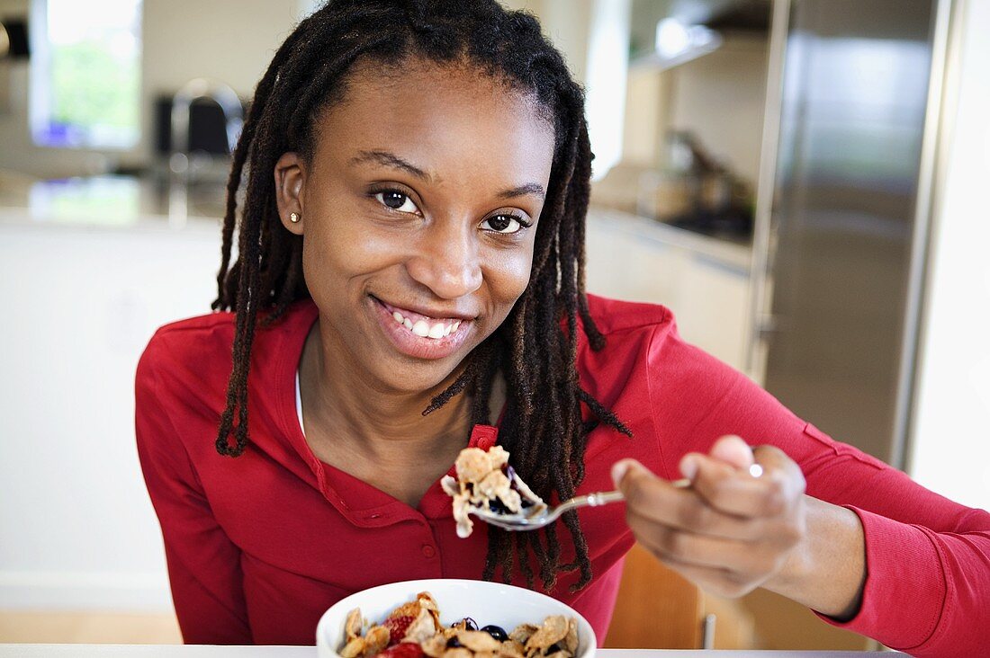 Junge Frau isst Müsli mit frischen Beeren