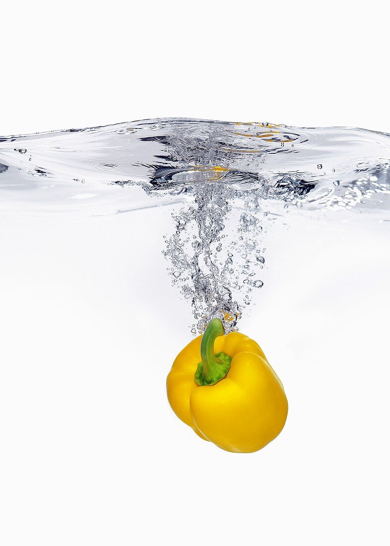 Gelber Paprika fällt ins Wasser
