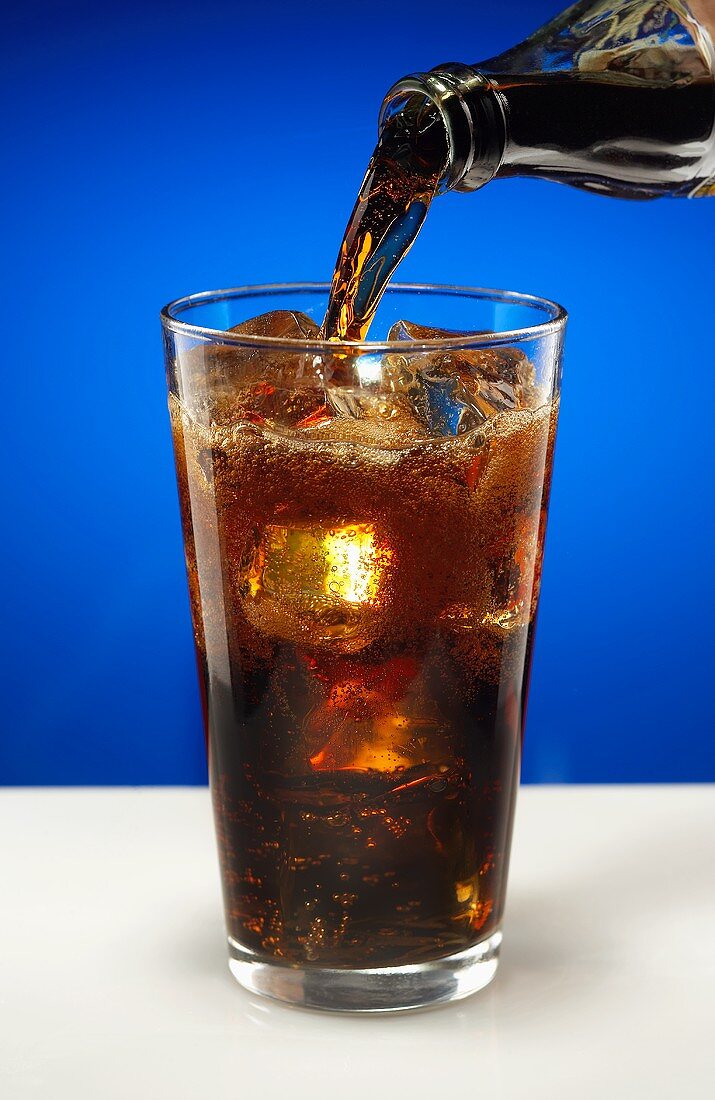 Cola aus Flasche in Glas einschenken