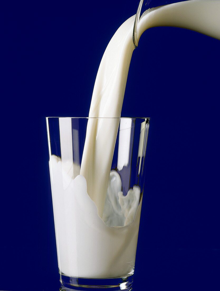 Milch aus Glaskrug in Glas gießen