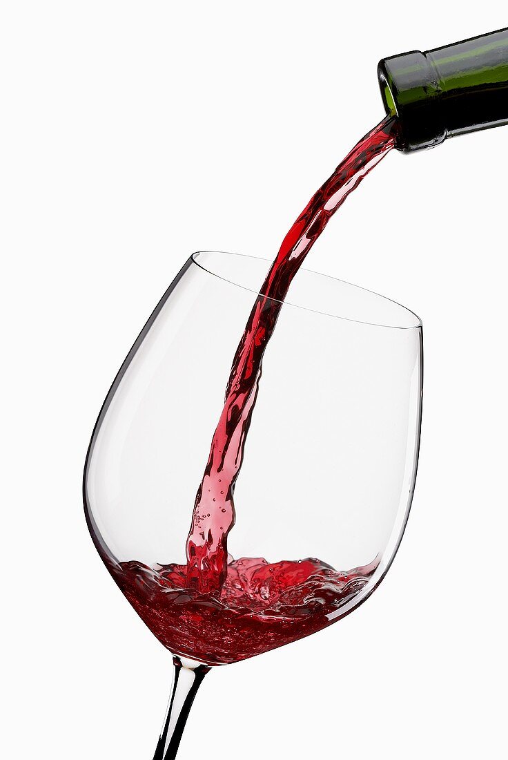 Rotwein aus Flasche in Glas einschenken