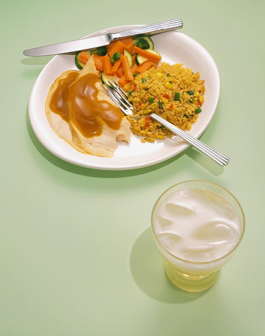 Putenscheiben mit Sauce, Reis, Gemüse und Glas Ginger Ale