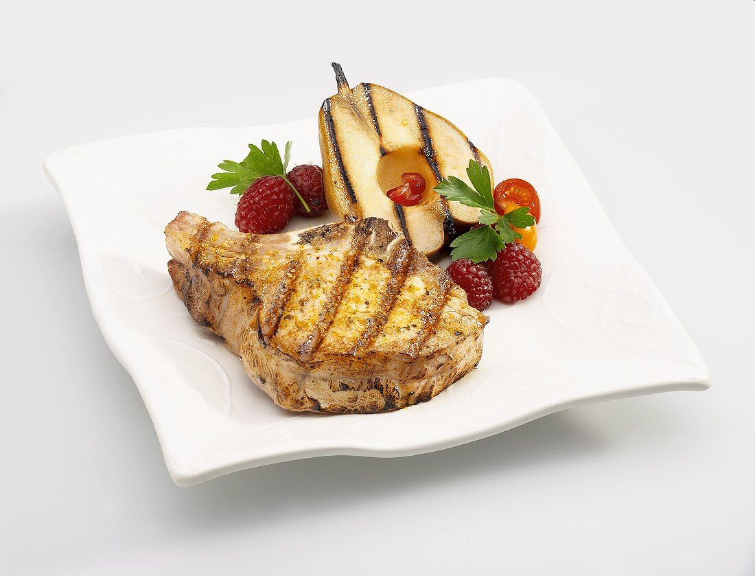 A Grilled Pork Chop with a Grilled Pear Slice and Raspberries