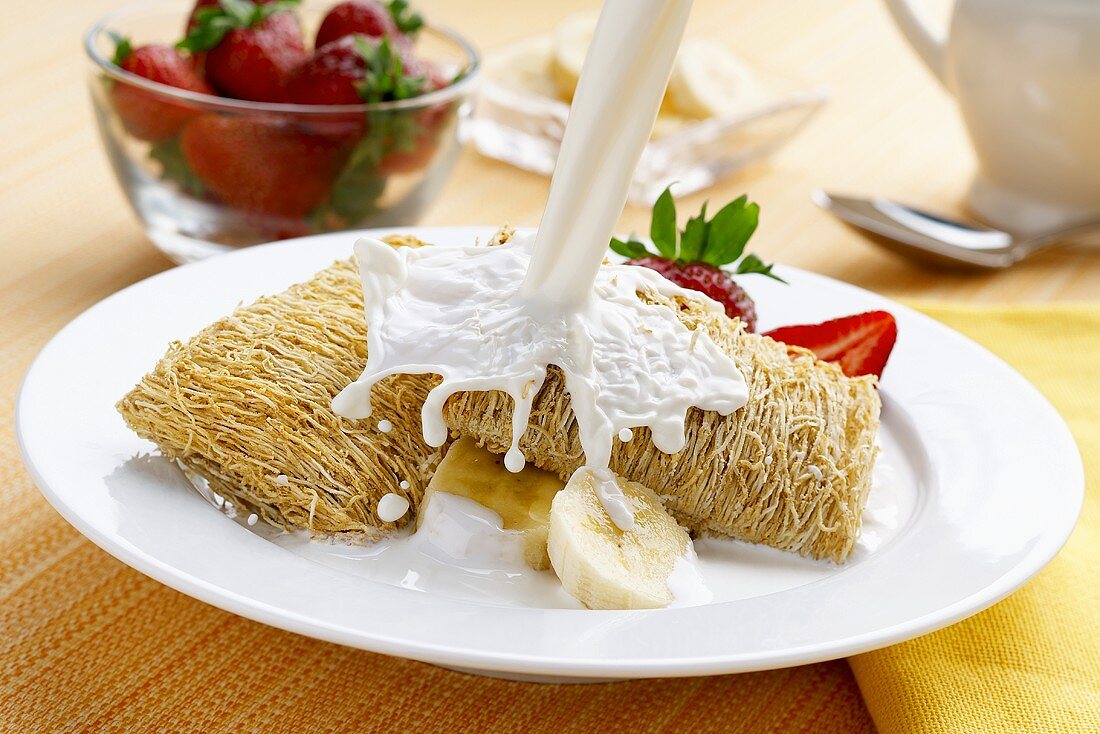 Milk Splashing Over Shredded Wheat Cereal with Bananas and Strawberries
