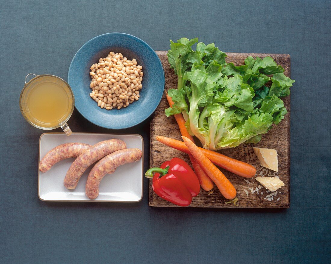 Zutaten für Gemüsesuppe mit weissen Bohnen, Salat und Wurst