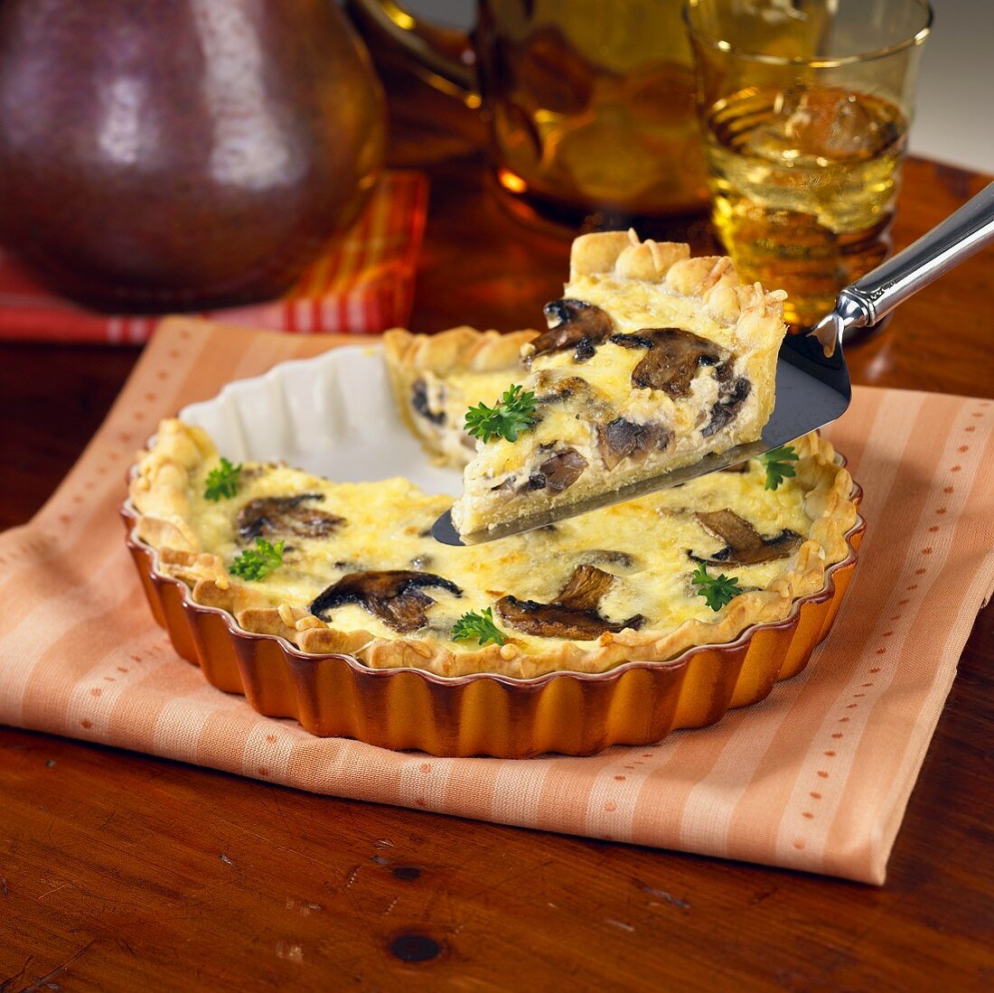 A Slice of Mushroom Quiche Being Lifted from the Pan on a Spatula