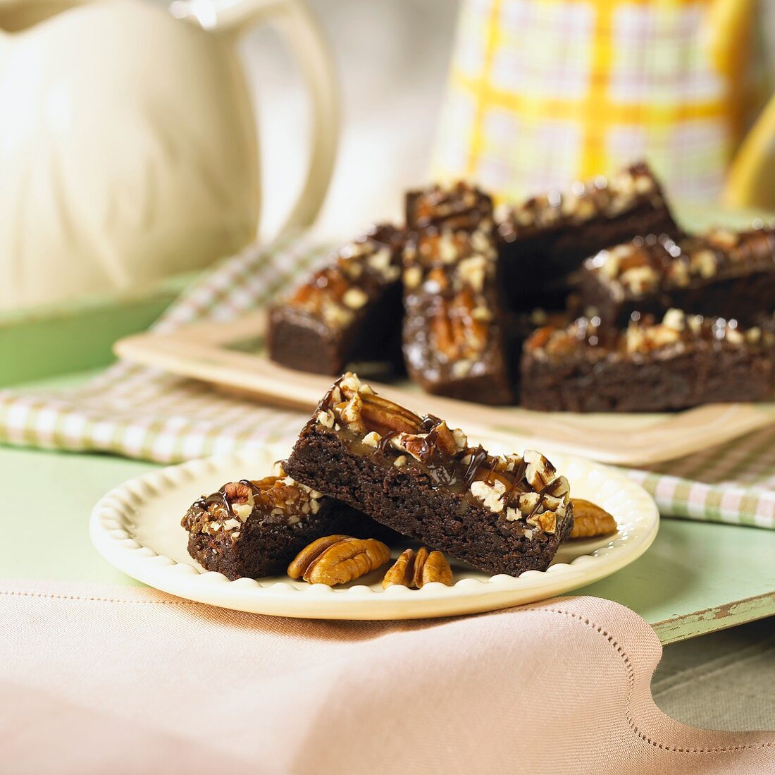 Caramel & pecan brownie bars on a plate and on a tray