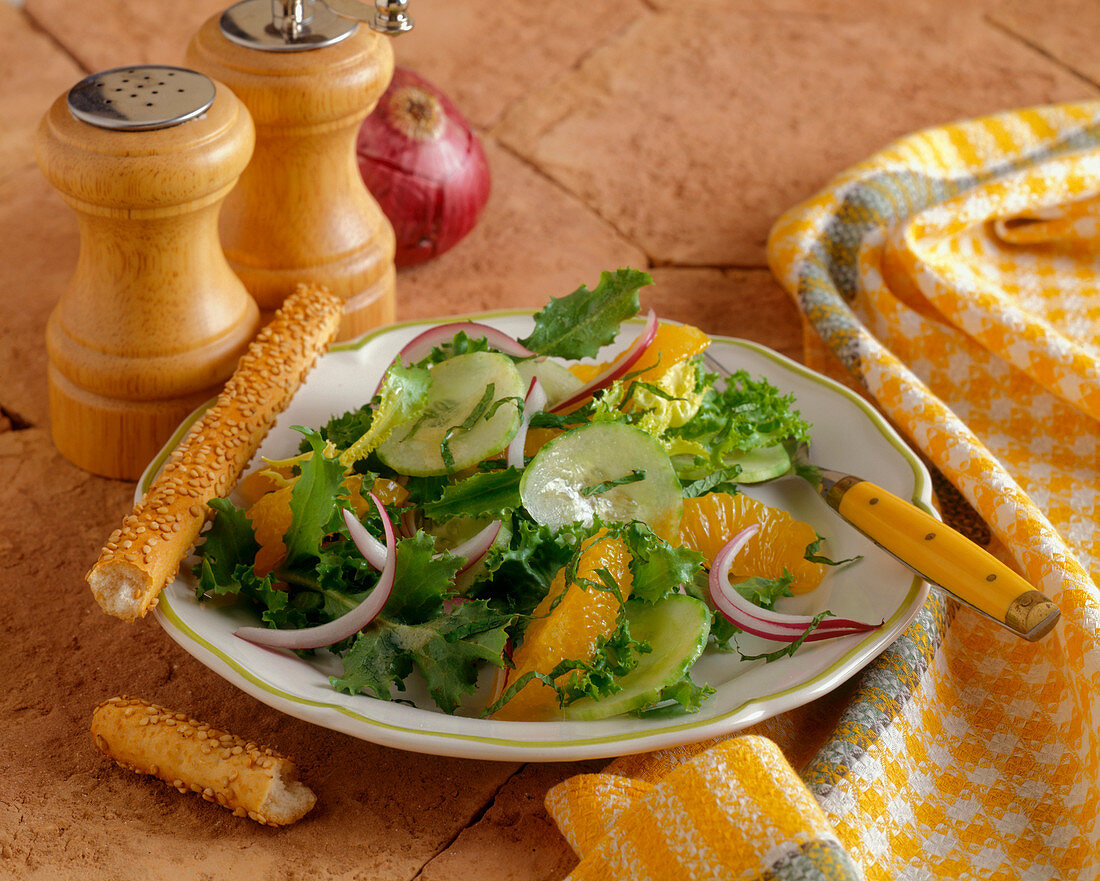 A Green Salad with Orange Segments and a Sesame Breadstick