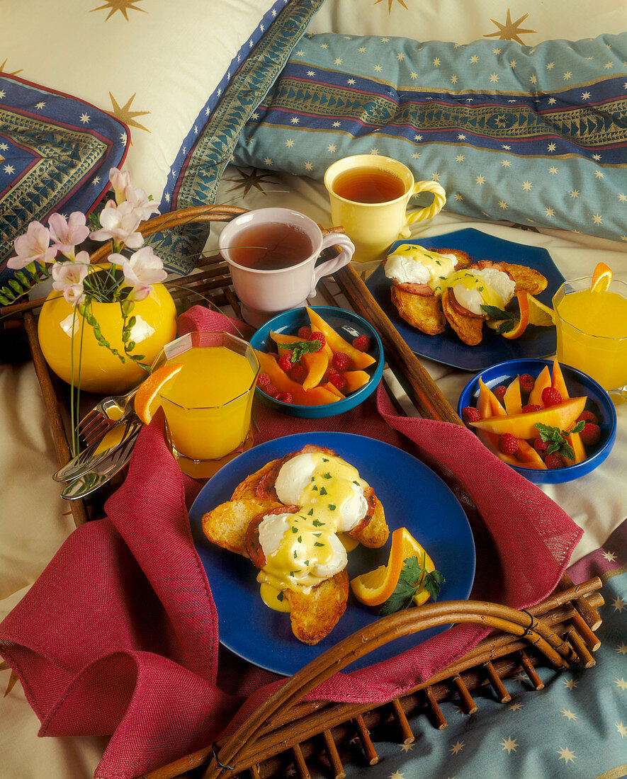 Frühstück mit Eggs Benedict, Obst, Orangensaft und Tee (USA)
