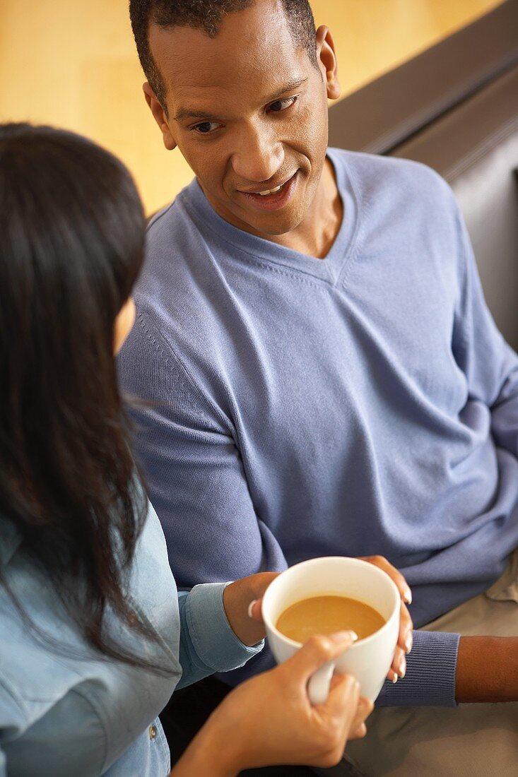 Frau mit Kaffeetasse neben Mann auf dem Sofa