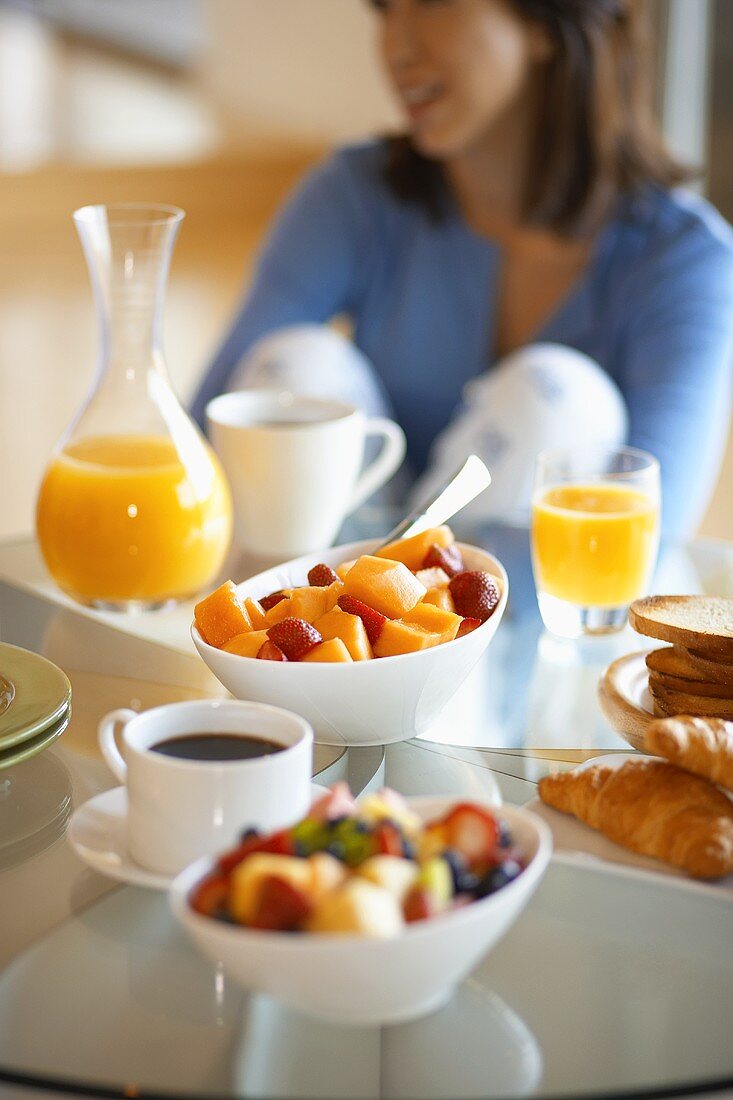 Frau beim gesunden Frühstück mit Obstsalat und Orangensaft