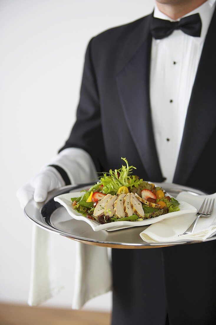 Butler serviert Hähnchensalat auf Silbertablett