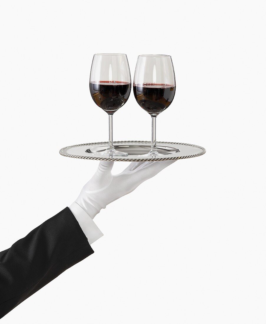 A Gloved Hand Holding a Silver Tray with Two Glasses of Red Wine