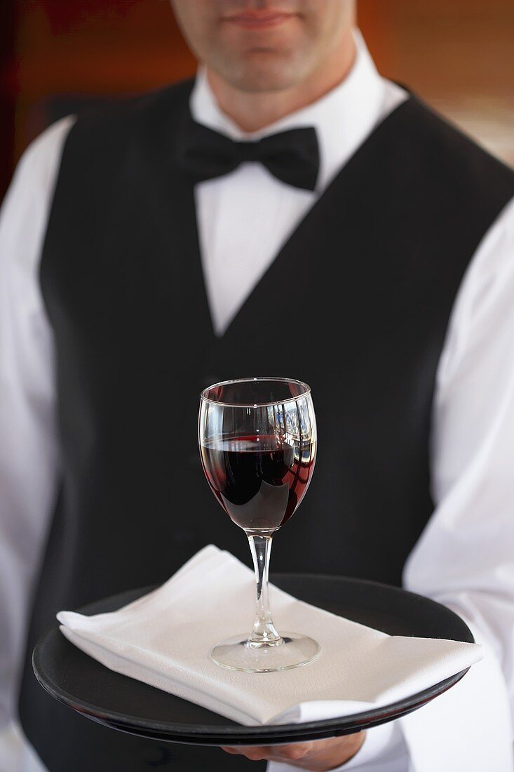 Kellner serviert Glas Rotwein