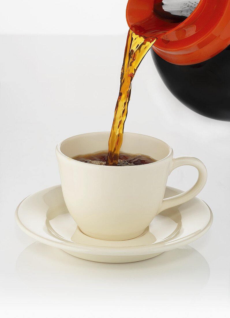 Kaffee aus Kanne in Tasse gießen