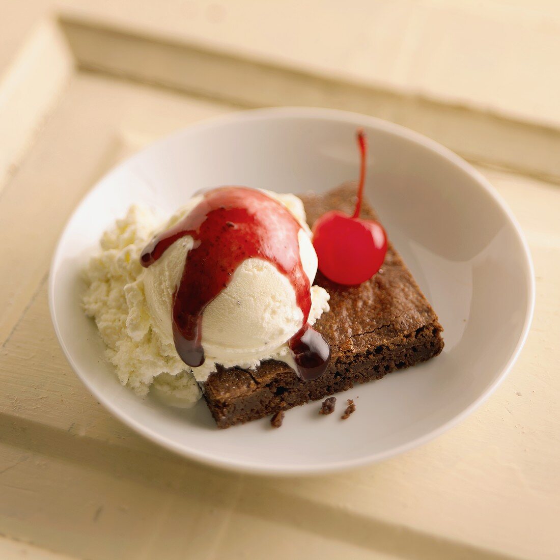 Brownie mit Vanilleeis, Kirschsauce und Cocktailkirsche