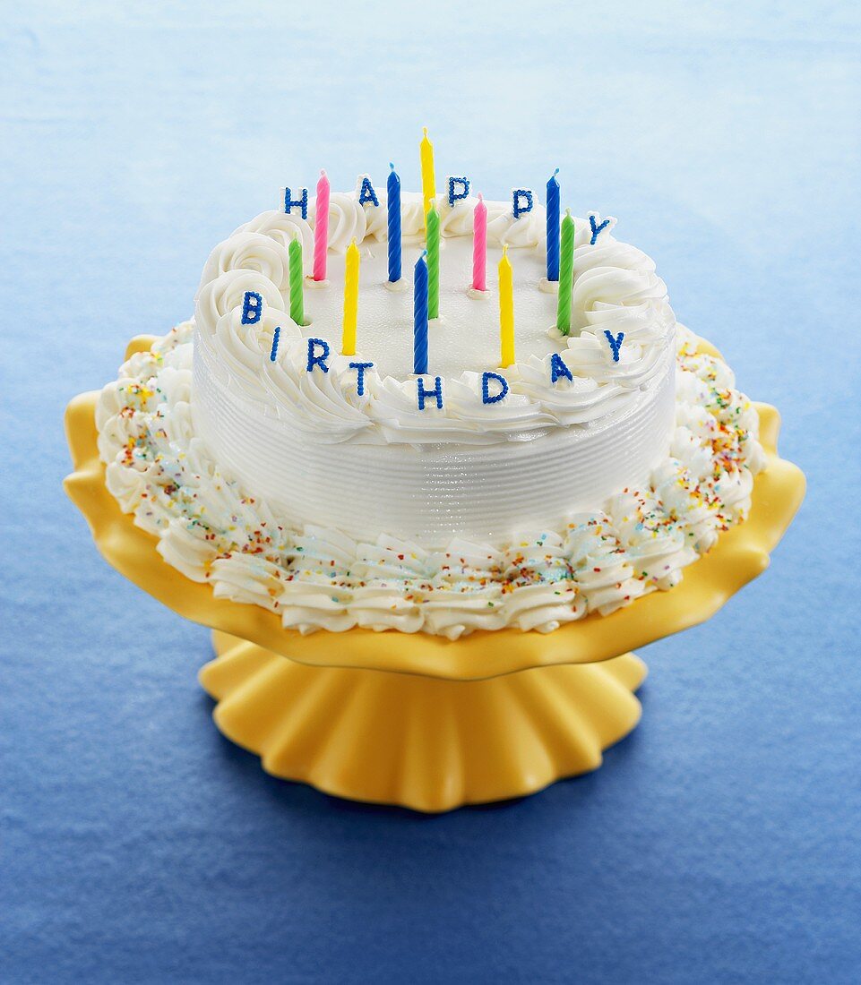 A Birthday Cake on an Orange Stand with Un-Lit Candles