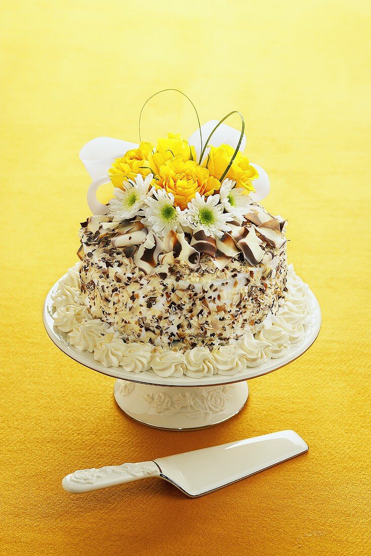 A Cake with White Frosting and White and Milk Chocolate Ribbons and Pieces