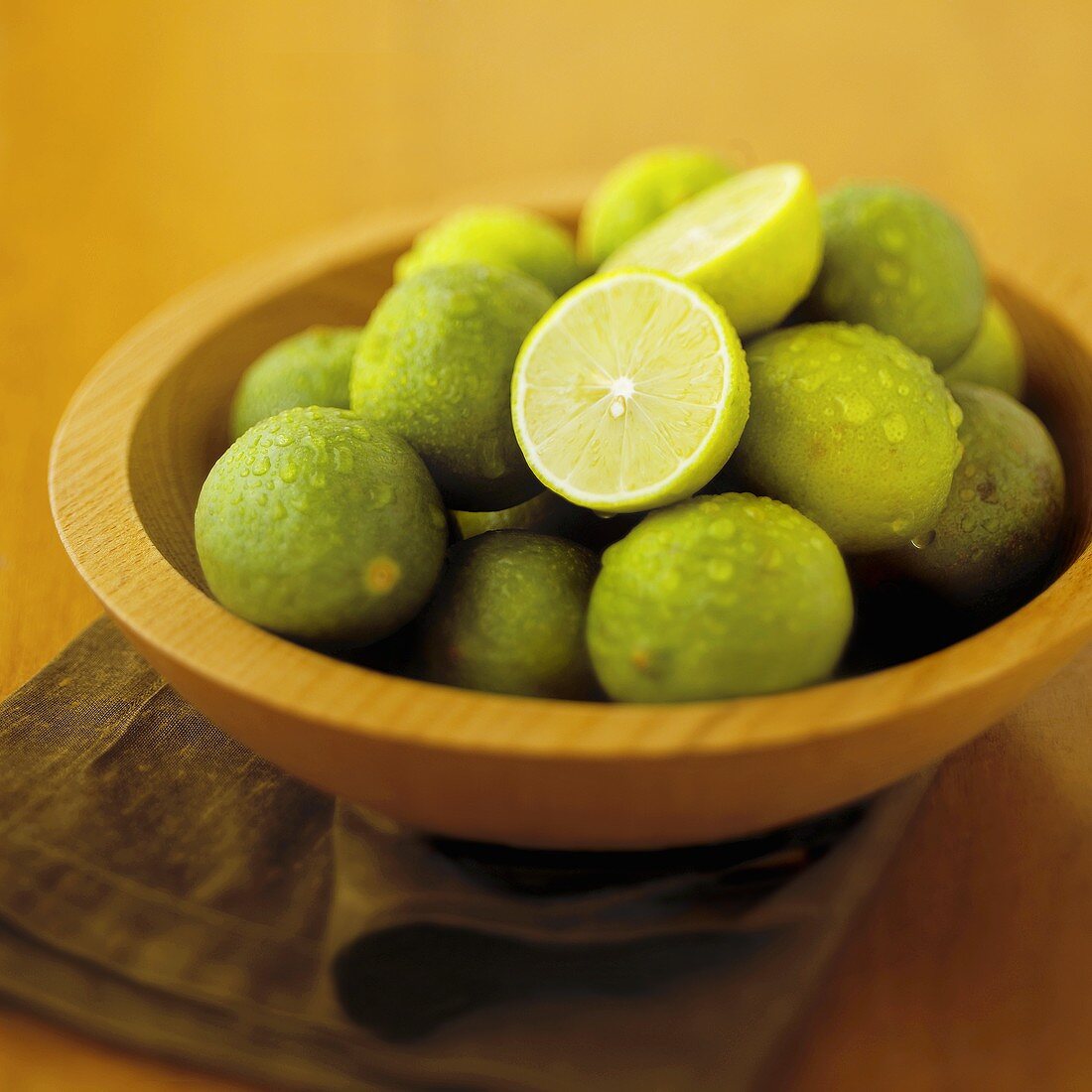 Limetten mit Wassertropfen in Holzschale