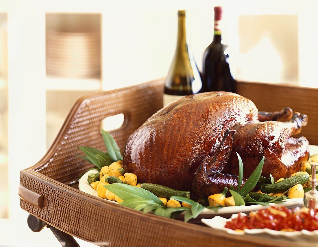 A Whole Roast Turkey on a Wicker Tray with Wine Bottles and Side Dishes