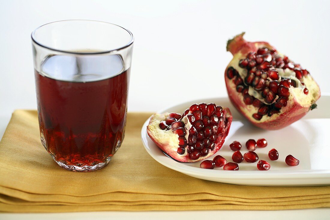 A Glass of Pomegranate Juice with an Opened Pomegranate