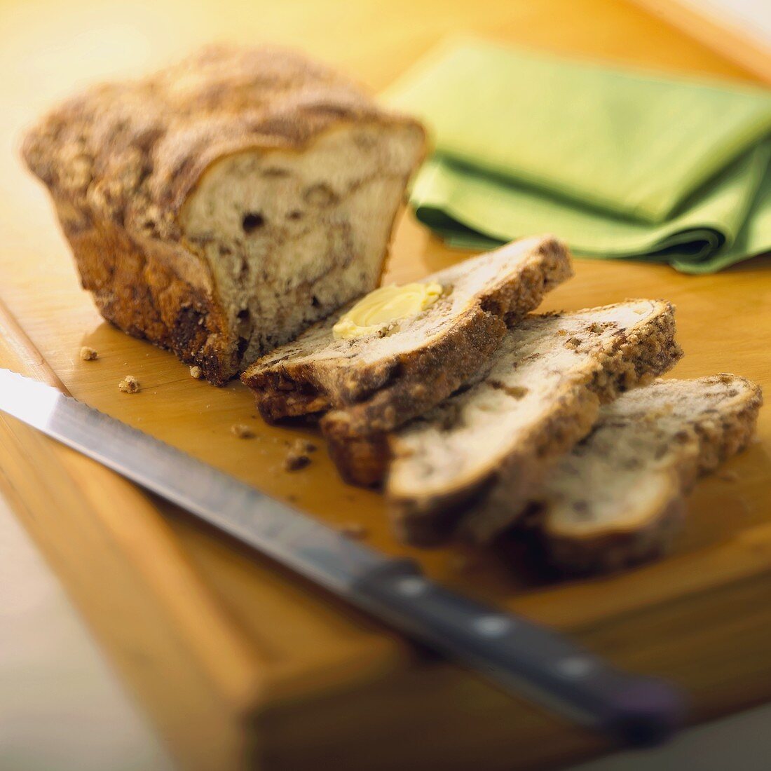 A Partially Sliced Loaf of Cinnamon Apple Bread on a Wooden Board with a Knife