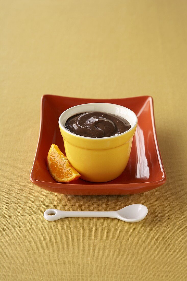Schokoladenpudding in gelbem Schälchen, Orangenschnitz
