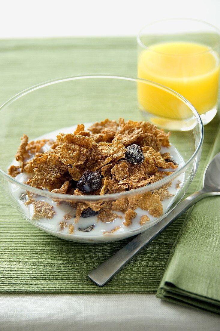 A Bowl of Bran Flake Cereal with Raisins and a Glass of Orange Juice