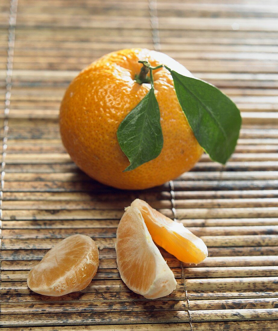 Tangerine mit Blättern und drei Tangerinenspalten
