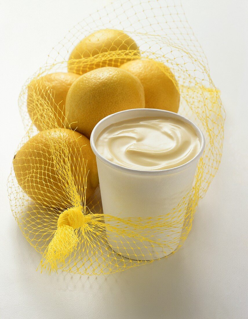 Joghurt im Becher mit Zitronen im Netz