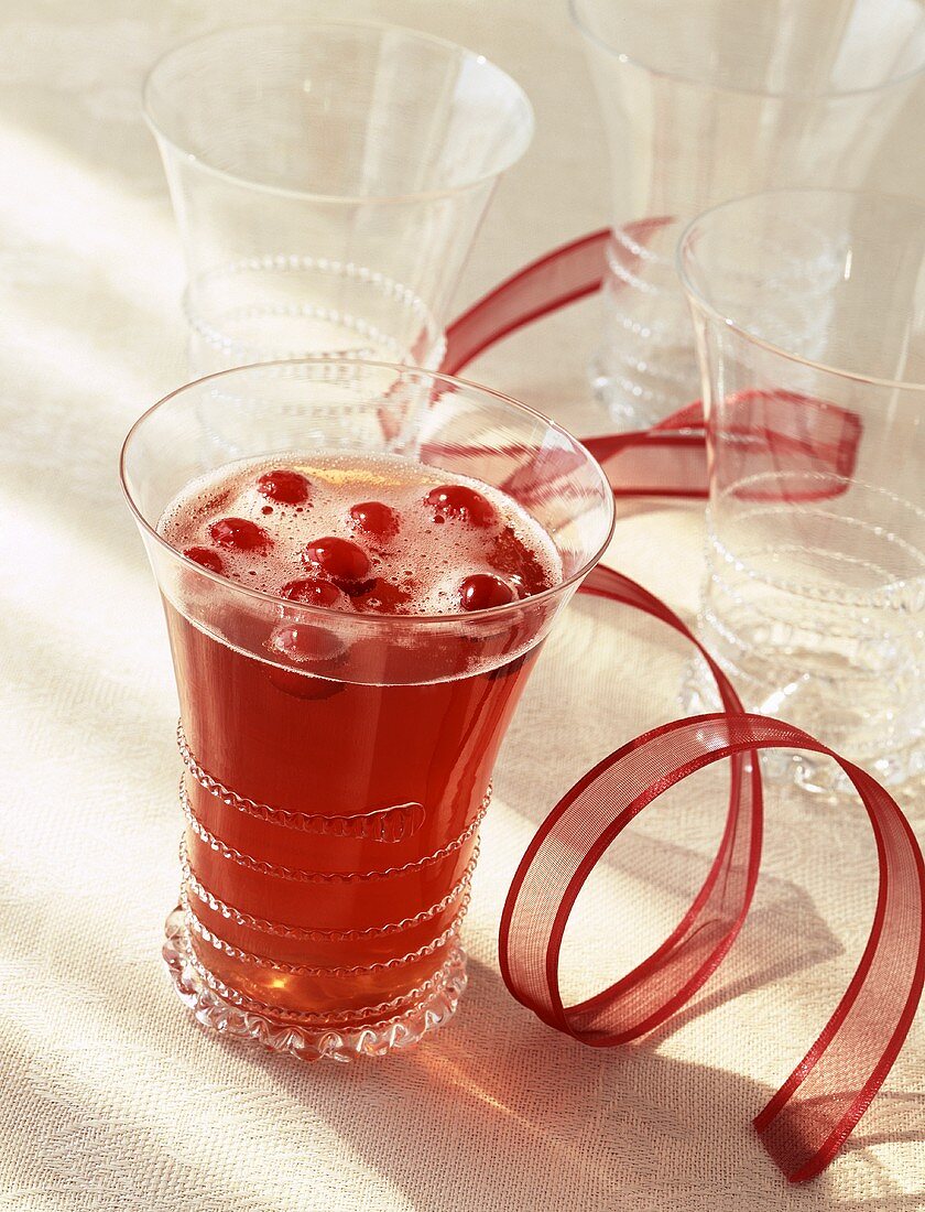 Cranberrycocktail, leere Gläser und rote Schleife